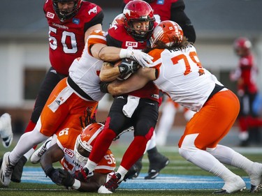 BC Lions' Adam Bighill, left, and David Menard, right sack Calgary Stampeders' quarterback Bo Levi Mitchell during first half CFL football action in Calgary, Friday, July 29, 2016.