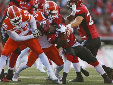 Calgary Stampeders' Roy Finch is tackled by B.C. Lions' Darius Allen, left, and Steven Clarke during first half CFL football action in Calgary, Friday, July 29, 2016.