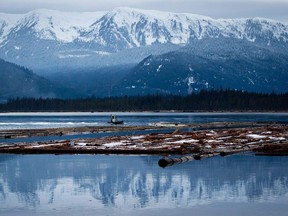 A worker uses a small boat to move logs on the Douglas Channel at dusk in Kitimat, B.C. Douglas Channel is the proposed termination point for an for an oil pipeline from Alberta as part of the Enbridge Northern Gateway Project.