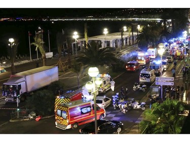 Emergency services vehicles work on the scene after a truck, left, plowed through Bastille Day revelers in the French resort city of Nice, France, Thursday, July 14, 2016. France was ravaged by its third attack in two years when a large white truck mowed through revelers gathered for Bastille Day fireworks in Nice, killing at dozens of people as it bore down on the crowd for more than a mile along the Riviera city's famed seaside promenade.