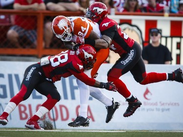 BC Lions' Emmanuel Arceneaux, centre, is tackled by Calgary Stampeders' Brandon Smith, left, and Joe Burnett during first half CFL football action in Calgary, Friday, July 29, 2016.