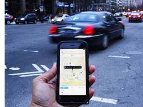This file photo taken on March 25, 2015 shows an UBER application being shown as cars drive by in Washington, DC. New Uber ads discuss long wait times for traditional taxis in places like Surrey, and detail how B.C. is falling behind Seattle, Toronto and other major cities in allowing the service.