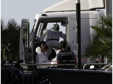 Forensic police officers work at the truck that plowed into the crowd in Nice, southern France, Friday July 15, 2016.  A large truck plowed through revelers gathered for Bastille Day fireworks in Nice, killing more than 80 people and sending others fleeing into the sea as it bore down for more than a mile along the Riviera city's famed waterfront promenade.