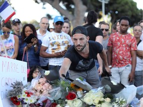 A man lays flowers at a makeshift memorial to pay tribute to the victims of an attack in the French Riviera city of Nice on July 15, 2016, a day after when a man rammed a truck through a crowd celebrating Bastille Day, killing at least 84 people. /