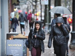 Gastown shopper try to shelter themselves from heavy rain as wet weather continues in Vancouver on Sunday, March 13, 2016.