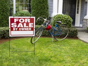 Closeup view of Modern Suburban Home with for Sale Real Estate Sign in front yard and bicycle and house in background
