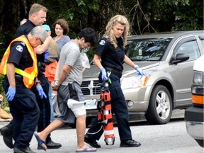 A man with burns and on oxygen is taken away in handcuffs from the scene of a house fire that injured two adults and five children in Port Moody on July 10. 2016.
