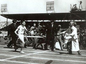 Jim Peters, left, stumbles towards the finish line as Mick Mayes, England's team masseuse, intercepted him and put an end to one of the most dramatic finishes in marathon history.