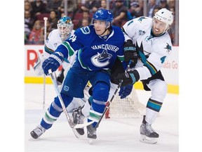 San Jose Sharks #4 Brenden Dillon clears the puck around Vancouver Canucks #14 Alex Burrows in the third period of a regular season NHL hockey game at Rogers arena, March 29 2016.