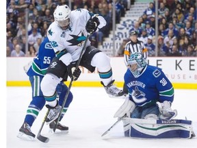 San Jose Sharks’ Joel Ward, left, jumps to avoid the puck as Vancouver Canucks goalie Ryan Miller makes the save during the first period of an NHL hockey game in Vancouver, B.C., on Thursday March 3, 2016.