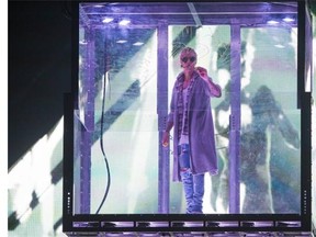 Justin Bieber writes on the wall of a glass box during his concert at Rogers Arena in Vancouver on March 11.