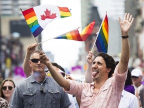 Prime Minister Justin Trudeau waves a flag as he takes part in the annual Pride Parade in Toronto on Sunday, July 3, 2016.
