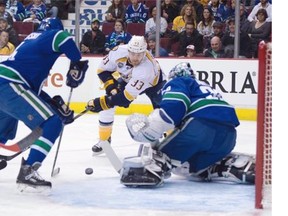 Nashville Predators’ centre Colin Wilson (33) tries to get a shot past Vancouver Canucks’ goalie Ryan Miller (30) as the Canucks’ defenceman Matt Bartkowski (44) looks on during first period NHL action in Vancouver on Saturday, March 12, 2016.