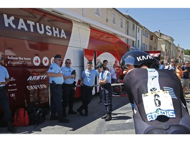 Netherlands' Wouter Poels looks back as he passes French gendarmes guarding the Katusha team bus during the thirteenth stage of the Tour de France cycling race, an individual time trial over 37.5 kilometers (23 miles) with start in Bourg-Saint-Andeol and finish in La Caverne du Pont-d'Arc, France, Friday, July 15, 2016. A Frenchman of Tunisian descent drove a truck through crowds celebrating Bastille Day along Nice's beachfront, killing at least 84 people, many of them children.