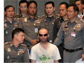 Christopher Paul Neil is surrounded by Thai policemen during a press conference at the Police Bureau in Bangkok, 19 October 2007.