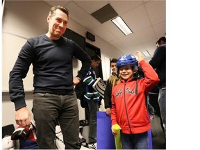 Kirk McLean, Vancouver Canucks alumni, treats the young Syrian refugees with hands on instruction during their Hockey 101 session. Syrian children and families toured Rogers Arena and learned a few hockey tips before watching a game March 21, 2016.