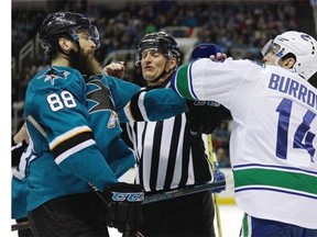 An official separates Vancouver Canucks’ Alex Burrows, right, from San Jose Sharks’ Brent Burns during the third period of an NHL hockey game Saturday, March 5, 2016, in San Jose, Calif. Vancouver won 4-2.