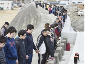 People observe a moment of silence for the victims of the 2011 earthquake and tsunami, on a seawall in Miyako, Iwate prefecture, in northern Japan on March 11.