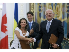 Canadian International Trade Minister Chrystia Freeland, foreground left, shaks hands with the First Vice Prime Minister, Minister of Economic Development and Trade of Ukraine Stepan Kubiv, foreground right, as Ukrainian President Petro Poroshenko, behind him, and Canadian Prime Minister Justin Trudeau, left, applaud during a signing ceremony in Kiev, Ukraine, Monday, July 11, 2016. Trudeau oversaw the signing of a free trade agreement with Ukraine on Monday after he and his son spent the morning commemorating the victims of mass atrocities perpetrated by the Nazis and Soviets.