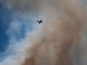 A firefighting plane navigates through smoke from a wildfire burning at Burns Bog in Delta, B.C., on Sunday, July 3, 2016.
