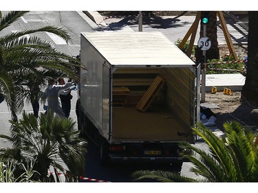 Police officers work at the  truck that mowed through revelers in Nice, southern France, Friday, July 15, 2016.  A large truck mowed through revelers gathered for Bastille Day fireworks in Nice, killing more than 80 people and sending people fleeing into the sea as it bore down for more than a mile along the Riviera city's famed waterfront promenade.