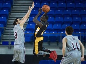Dalhousie Tigers' Ritchie Kanza Mata, centre, passes the ball as Ottawa Gee-Gees' Matt Plunkett, left, defends and Mike L'Africain watches during quarter-final CIS men's national university basketball championship action in Vancouver on Thursday, March 17, 2016.