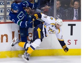 Vancouver Canucks' Ben Hutton, left, and Nashville Predators' Eric Nystrom collide during third period NHL hockey action, in Vancouver on Tuesday, Jan. 26, 2016.