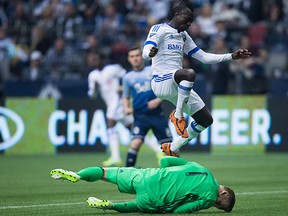 Montreal Impact's Dominic Oduro, top, of Ghana, leaps over Vancouver Whitecaps' goalkeeper David Ousted, of Denmark, as he makes a save during first half MLS soccer action, in Vancouver on Sunday, Mar. 6, 2016.