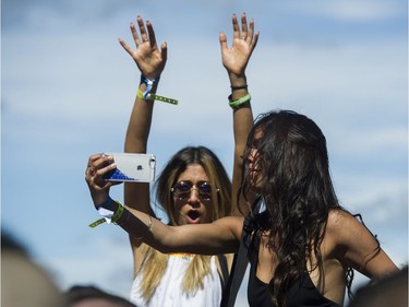 Two women sitting on shoulders take a selfie as Ekau performs at FVDED in the park at Holland park in Surrey on July 2, 2016.