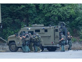 Heavily armed SWAT team members prepare to enter a gun store while searching for a person involved in a break-in July 19 in Marietta, Ga., near Atlanta.
