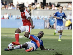 MLS All-Stars' Kendall Waston, bottom, of the Vancouver Whitecaps, makes a slide tackle under Arsenal's Theo Walcott .