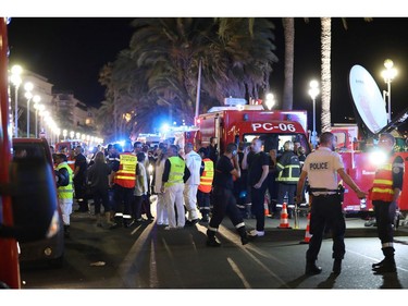 TOPSHOT - Police officers, firefighters and rescue workers are seen at the site of an attack on July 15, 2016, after a truck drove into a crowd watching a fireworks display in the French Riviera town of Nice. A truck ploughed into a crowd in the French resort of Nice on July 14, leaving at least 60 dead and scores injured in an "attack" after a Bastille Day fireworks display, prosecutors said on July 15.  /