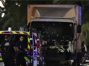 Police officers stand near a van, with its windscreen riddled with bullets, that ploughed into a crowd leaving a fireworks display in the French Riviera town of Nice on July 14, 2016. Up to 30 people are feared dead and over 100 others were injured after a van drove into a crowd watching Bastille Day fireworks in the French resort of Nice on July 14, a local official told French television, describing it as a "major criminal attack".