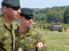 Canadian military instructors look on during Ukrainian military exercises at the International Peacekeeping and Security Center in Yavoriv, near Lviv, on July 12, 2016.