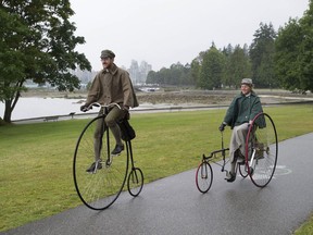 Gabriel Chrisman (left) rides his distinctive two-wheel, Victorian-era bicycle that was considered the 'Ferrari of its day,' in Stanley Park on Tuesday. Behind him, and aboard her late 19th-century tricycle, is his wife Sarah Chrisman. The tricycle, with a chain and drum brakes, made it more technologically advanced at that time than Gabriel's two-wheeler.