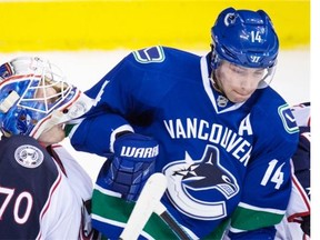 File: Vancouver Canucks Alex Burrows, right, bumps into Columbus Blue Jackets goalie Joonas Korpisalo, dislodging his mask, during the third period in Vancouver on Feb. 4.