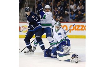 Vancouver Canucks’ goalie Jacob Markstrom (25) makes a toe save as Winnipeg Jets’ Mark Scheifele (55) battles the Canucks’ Matt Bartkowski (44) in front of the net during second period NHL hockey action in Winnipeg, Tuesday, March 22, 2016.