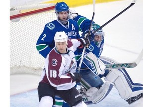 Vancouver Canucks goalie Ryan Miller (30) looks on as teammate Dan Hamhuis (2) tries to clear Colorado Avalanche center Shawn Matthias (18) from in front of the net during second period NHL action in Vancouver, B.C. Wednesday, March 16, 2016.
