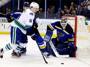Vancouver Canucks’ Jake Virtanen, left, controls the puck as St. Louis Blues goalie Brian Elliott defends during the first period of an NHL hockey game Friday, March 25, 2016, in St. Louis.