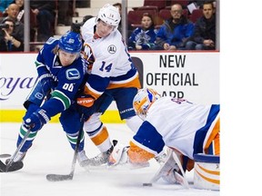 Vancouver Canucks #60 Markus Granlund and New York Islanders #14 Thomas Hickey digs for the puck  as goalie Tomas Greiss covers it up in the first period of a regular season NHL hockey game at Rogers Arena, Vancouver March 01 2016.