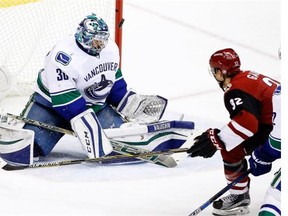 Vancouver Canucks’ Ryan Miller, left, makes a save on a shot by Arizona Coyotes’ Tyler Gaudet (32) during the second period of an NHL hockey game Wednesday, Feb. 10, 2016, in Glendale, Ariz.