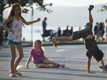 Children turn cartwheels at Beach Avenue  prior to the fireworks display from Team USA Disney at the Honda Celebration of Light at English Bay, Vancouver, July 30 2016.