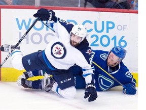 Winnipeg Jets centre Mathieu Perreault (85) puts Vancouver Canucks defenceman Alex Biega (55) into the boards during third period NHL action in Vancouver on Monday, March 14, 2016.