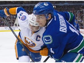 New York Islanders’ John Tavares, left, and Vancouver Canucks’ Alex Burrows battle for position.