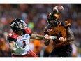 Calgary Stampeders' Lemar Durant, left, watches the ball but fails to make the reception as B.C. Lions' Ryan Phillips grabs his arm.