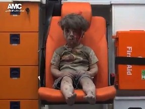 An image grab taken from a video uploaded by the Syrian opposition's activist group Aleppo Media Centre (AMC) on August 17, 2016 is said to show a young Syrian boy covered in dust and blood sitting in shock in an ambulance after being rescued from the rubble of a building hit by an air strike in the rebel-held Qaterji neighbourhood of the northern Syrian city of Aleppo.