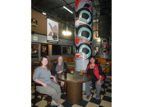 From left, Jo McRobb, Tom Detlor and Barbie Wallace. The three are sitting at the base of one of the Totems of the Balmoral Hotel in the Downtown Eastside on Tuesday. The totem was painted by artist Danny Dennis and efforts are being made to preserve it.