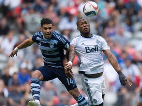 Sporting Kansas City's Dom Dwyer, of England, and Vancouver Whitecaps' Kendall Waston, of Costa Rica, vie for the ball.