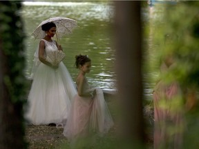 File: A bride holds an umbrella and walks in a park.
