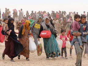 Syrian refugees carry their belongings as they wait to enter Jordanian side of the Hadalat border crossing, a military zone east of the capital Amman, after arriving from Syria.